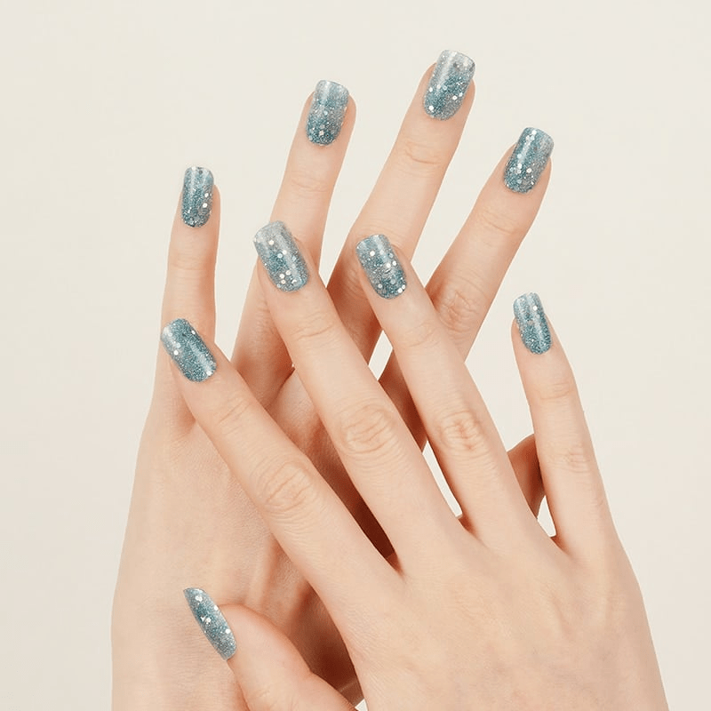 Icy blue glitter nail wraps with pearl accents applied on natural nails for winter look