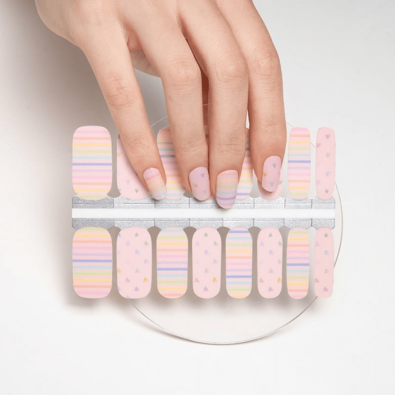 Hand selecting pastel rainbow striped nail wraps from sheet for DIY manicure