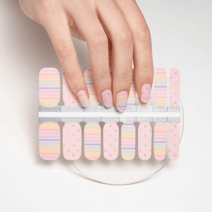 Hand selecting pastel rainbow striped nail wraps from sheet for DIY manicure
