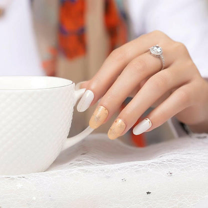 Nail wraps in white and nude with gold glitter star accents, glossy finish