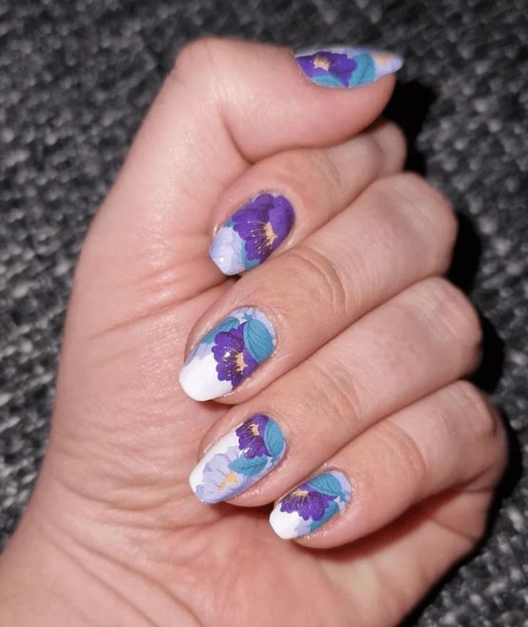 Hand wearing purple floral nail wraps with turquoise watercolour botanical pattern