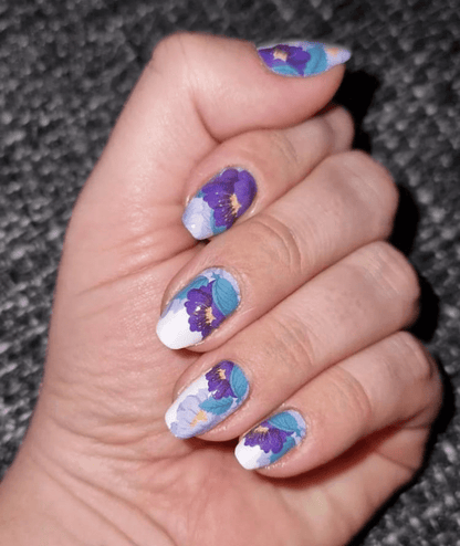 Hand wearing purple floral nail wraps with turquoise watercolour botanical pattern