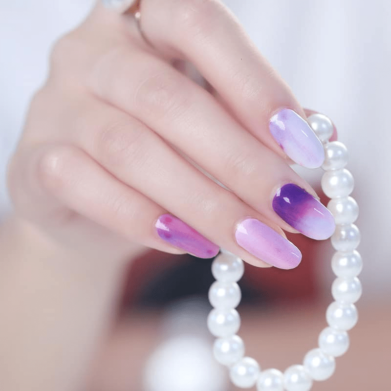 Glossy purple and pink watercolour-effect nail wraps on short round nails