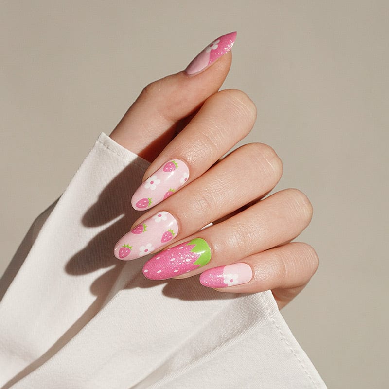 Pink and green strawberry pattern nail wraps on hand showing cute fruit nail art design