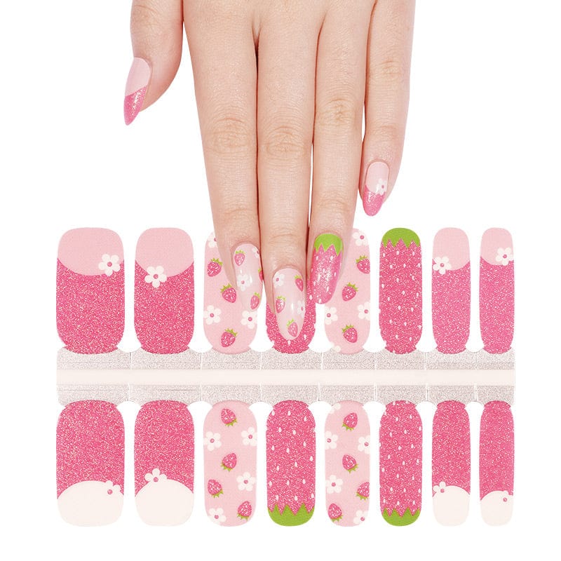 Hand selecting from pink strawberry nail wraps sheet with dotted and glitter finishes