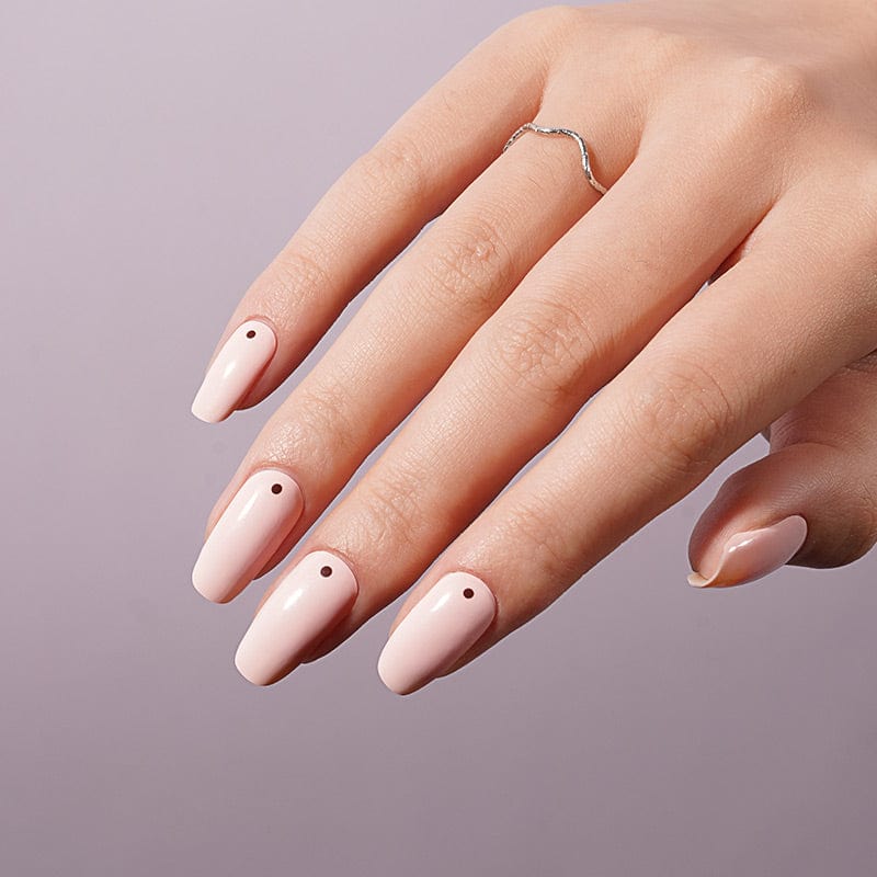 Nude-pink glossy nail wraps on coffin-shaped nails with a single tiny brown dot accent