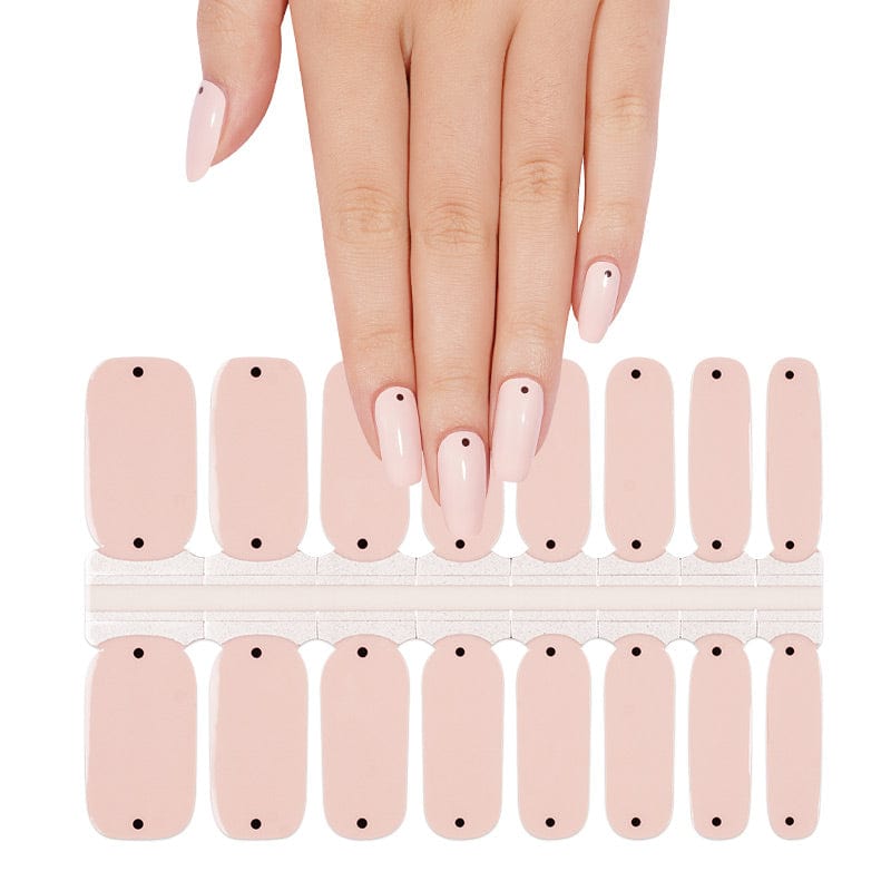Hand wearing nude pink polka dot nail wraps for elegant at-home manicure