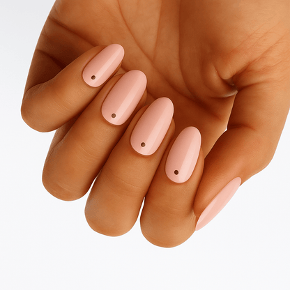Nude pink nail wraps with black polka dots on hand showing minimalist spot manicure