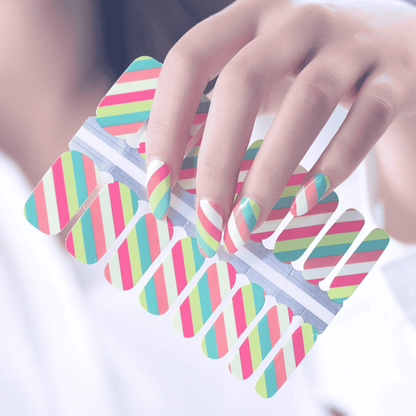 Hand holding multicoloured striped nail wraps with diagonal pink coral green patterns