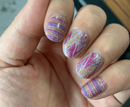 Glitter striped nail wraps on hand showing pink holographic watercolour finish