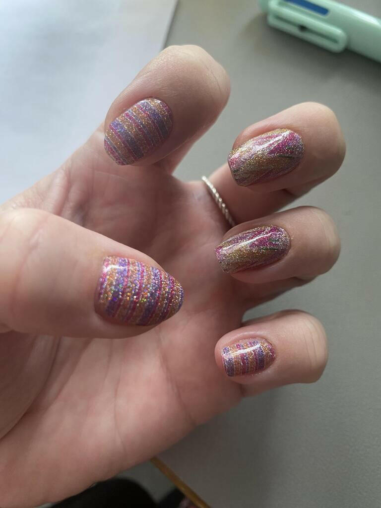 Pink holographic striped nail wraps on hand with shimmering watercolour effect