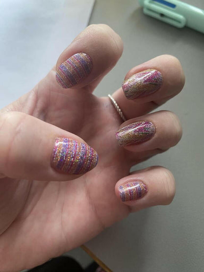 Pink holographic striped nail wraps on hand with shimmering watercolour effect