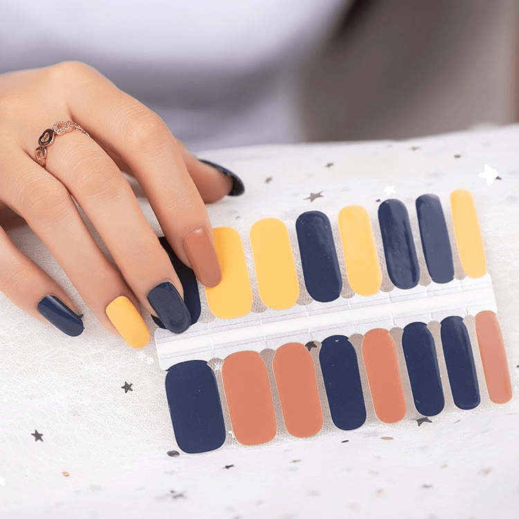 Hand applying navy blue and terracotta nail wraps from sheet