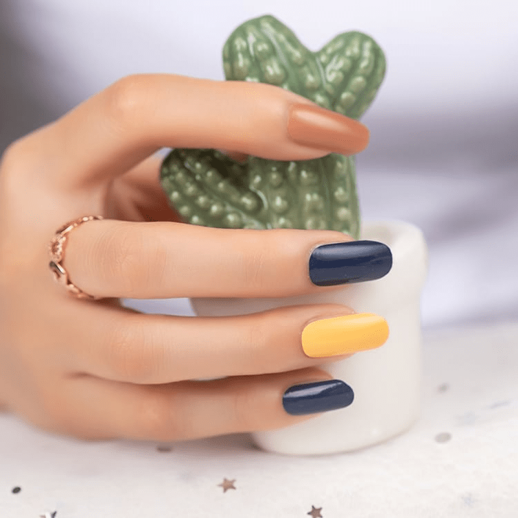 Hand holding cactus mug showing navy and yellow nail art wraps