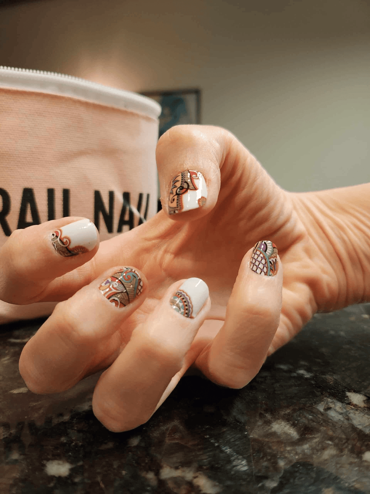 Hand wearing multicolour paisley nail wraps with intricate bohemian swirl designs on fingernails