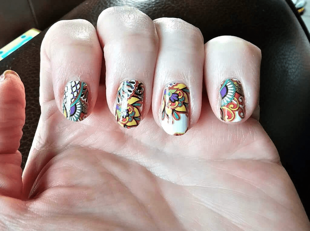 Hand displaying multicolour paisley nail art with bohemian swirl patterns on fingernails