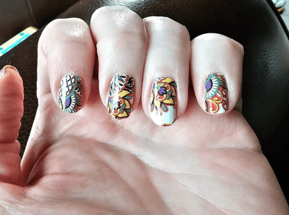 Hand displaying multicolour paisley nail art with bohemian swirl patterns on fingernails