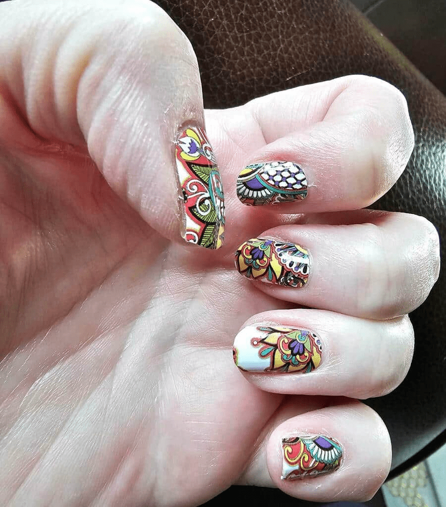 Hand wearing multicoloured paisley non-UV nail wraps with intricate bohemian patterns