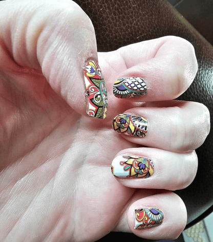 Hand wearing multicoloured paisley non-UV nail wraps with intricate bohemian patterns