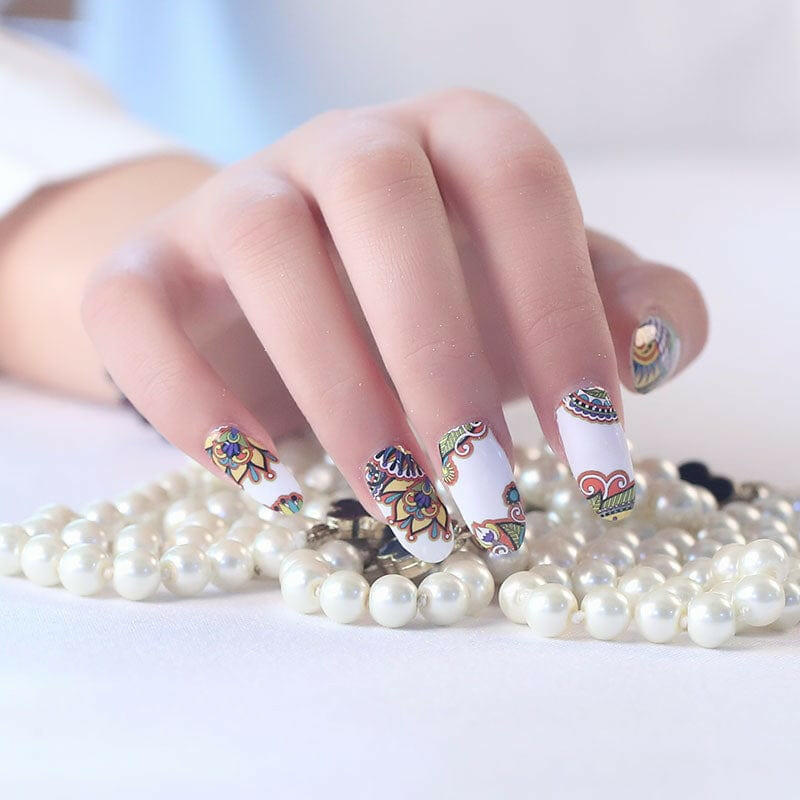 Hand with colourful paisley nail wraps touching pearl necklace showing boho nail art