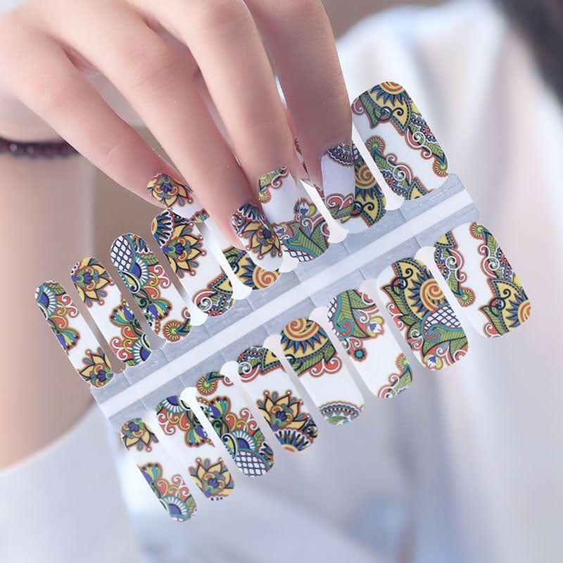 Hand holding sheet of multicolour paisley nail wraps with bohemian folk art patterns