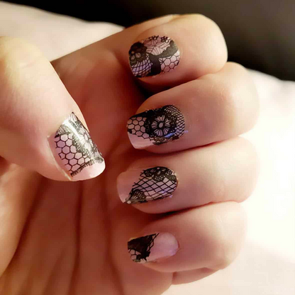 Black lace nail wraps applied on hand showing intricate gothic pattern manicure design