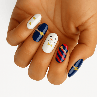 Christmas snowman nail wraps on hand featuring white nails with smiley faces and navy blue striped designs
