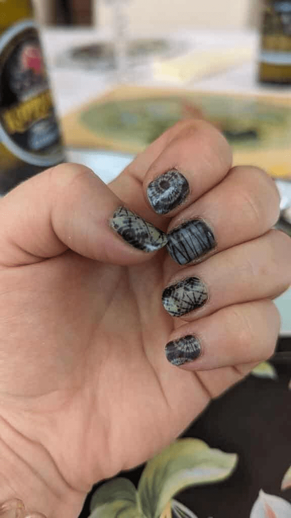 Nail wraps in black and grey tie-dye pattern on short, natural-shaped nails.