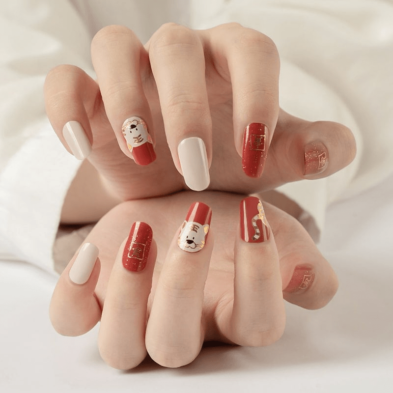 Red and white nail wraps with cute tiger character designs on hands