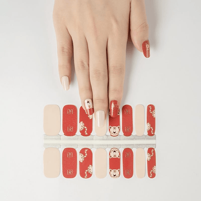 Non-UV nail wraps featuring red tiger characters with hand showing application