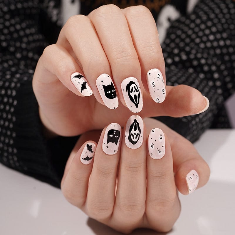 Halloween nail art with black and white ghosts, cats and spooky designs on hands