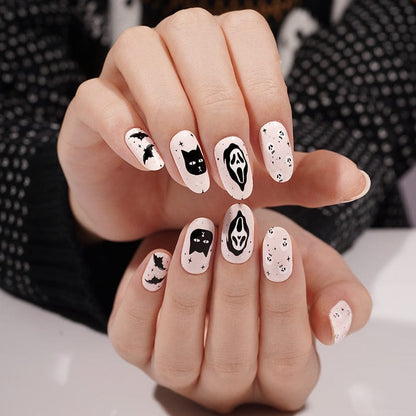 Halloween nail art with black and white ghosts, cats and spooky designs on hands