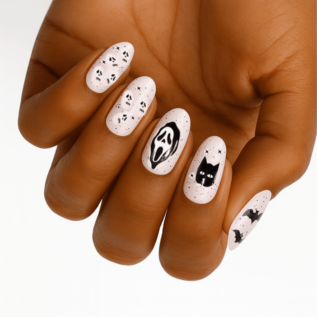 Hand wearing Halloween nail wraps with black cats, ghosts and Scream designs on white base