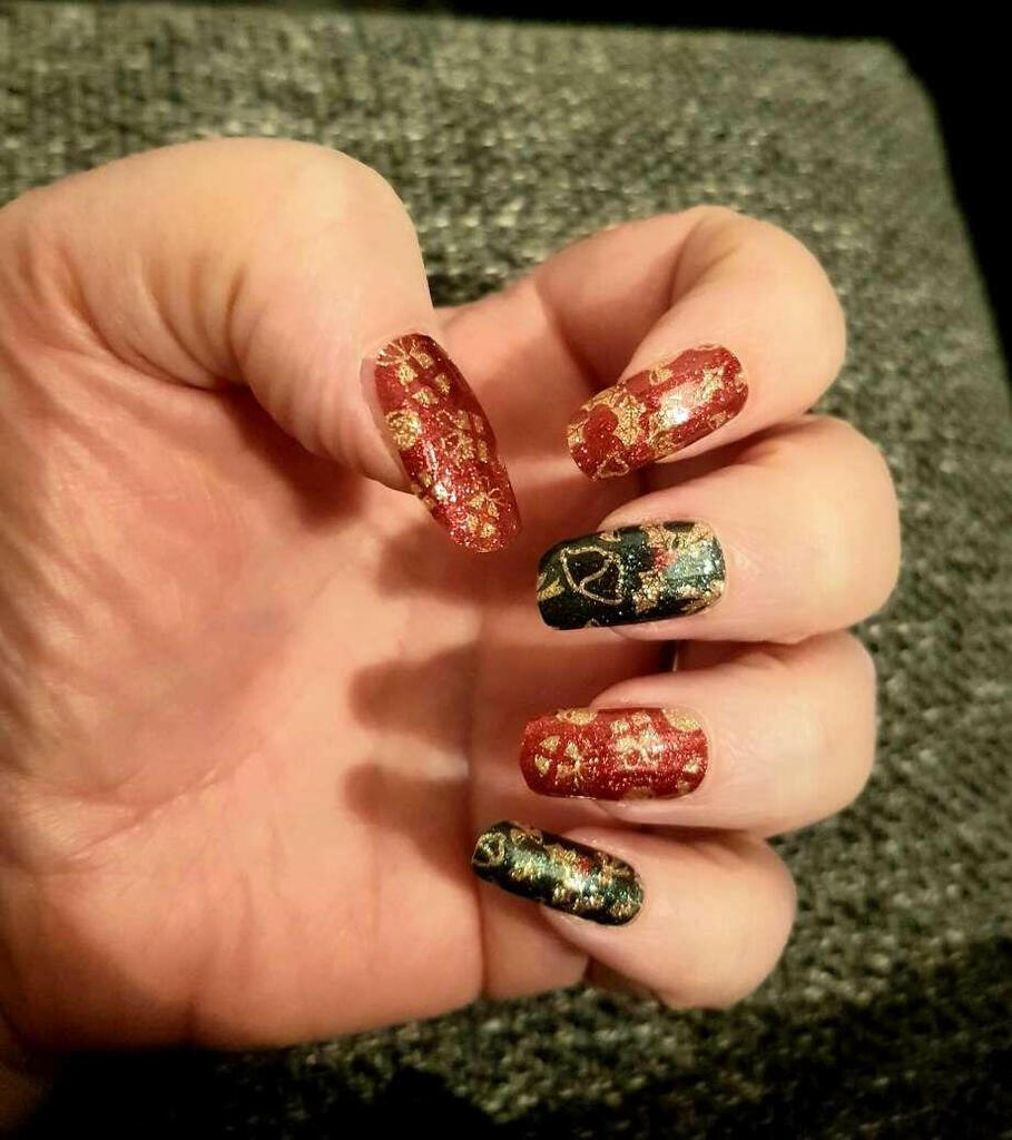 Festive Christmas nail wraps on hand featuring red glitter and green foil patterns