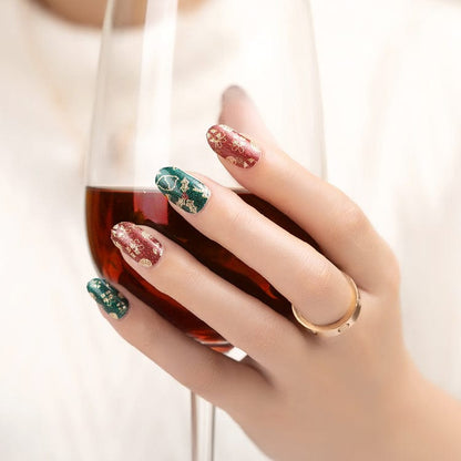 Hand holding wine glass with Christmas nail art featuring red and green glitter designs