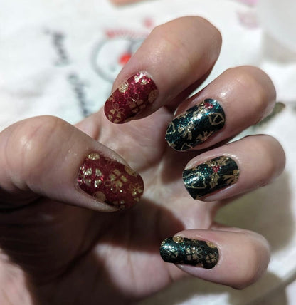 Red and green Christmas nail wraps on hand with holly leaf festive nail designs