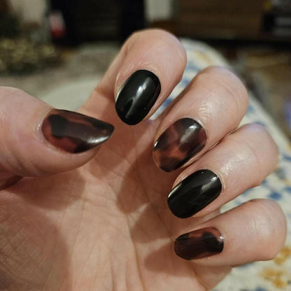 Black and brown tortoiseshell nail wraps on hand showing glossy animal print manicure