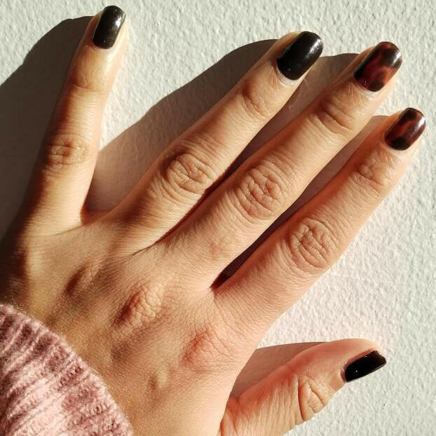 Glossy dark tortoiseshell nail wraps in deep brown-black tones on short round nails