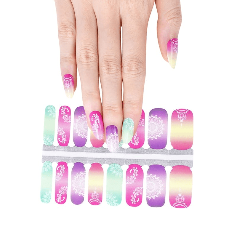Hand applying tropical ombre nail wraps with mandala patterns over wrap sheet