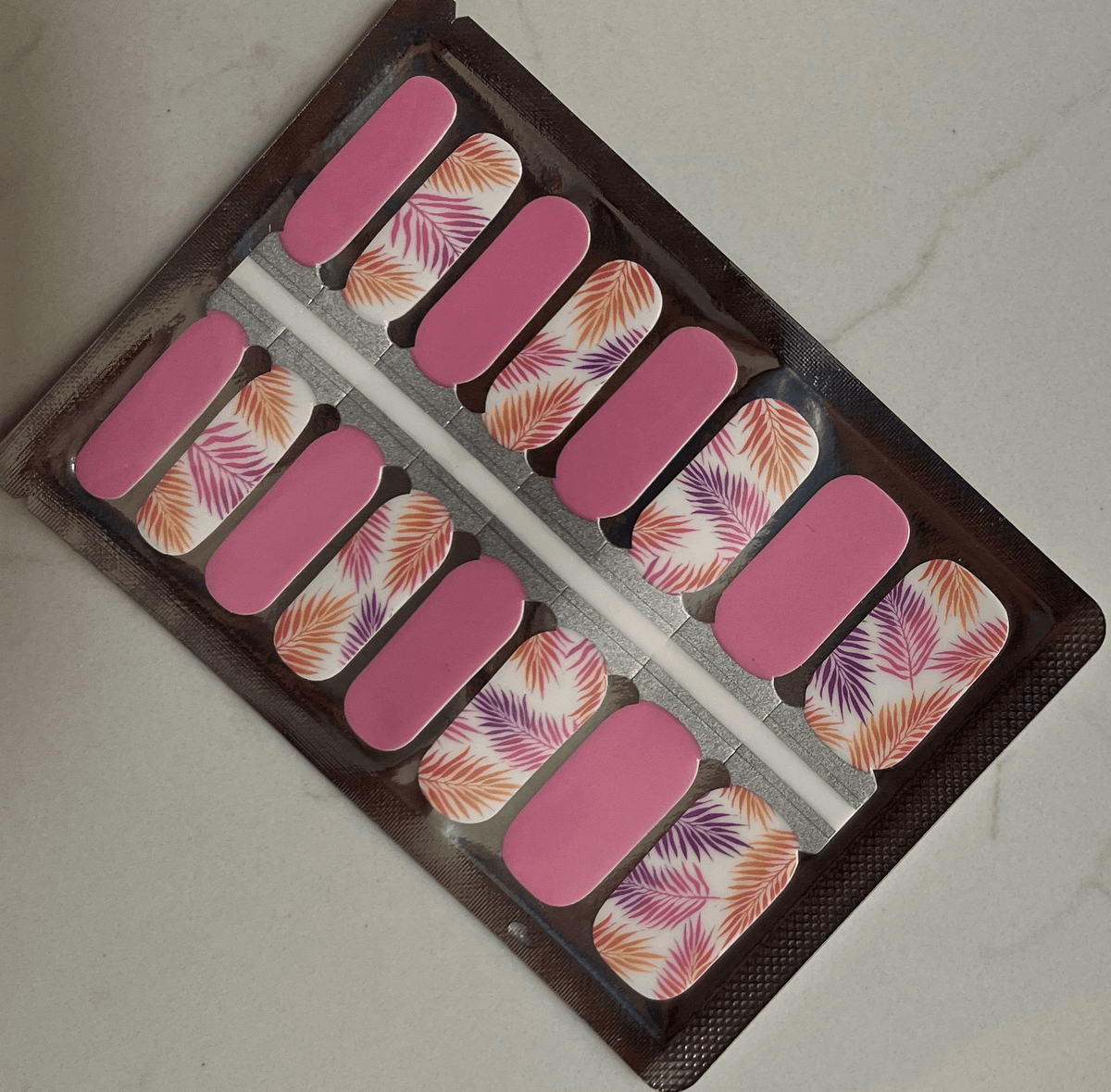 Pink coral nail wraps with tropical fern leaf pattern in packaging