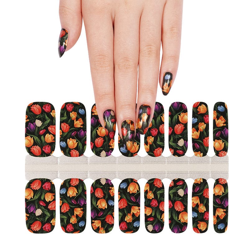 Hand holding sheet of dark floral tulip nail wraps for at-home manicure