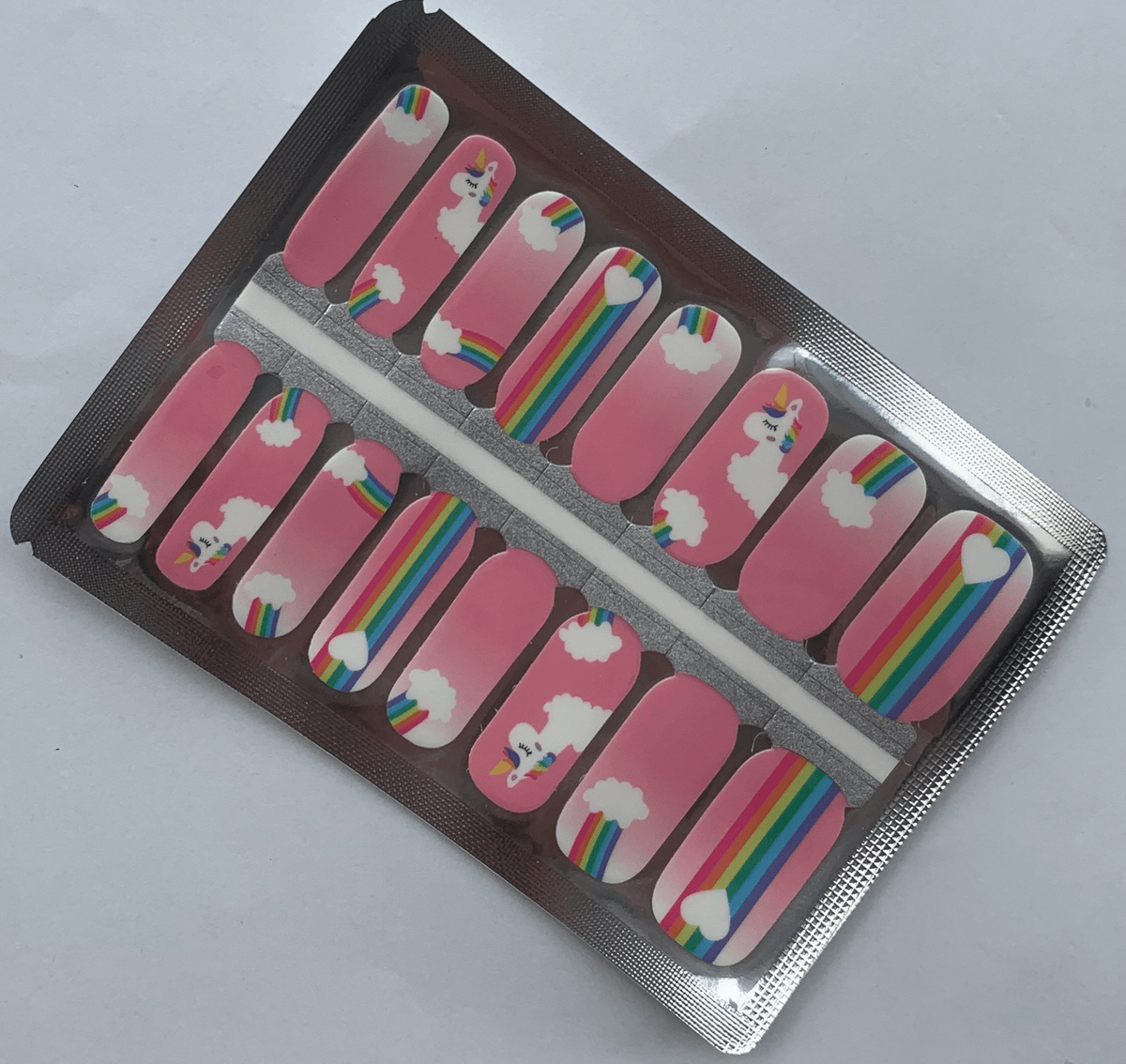 Pink nail wraps with colourful unicorn and rainbow cartoon patterns in packaging