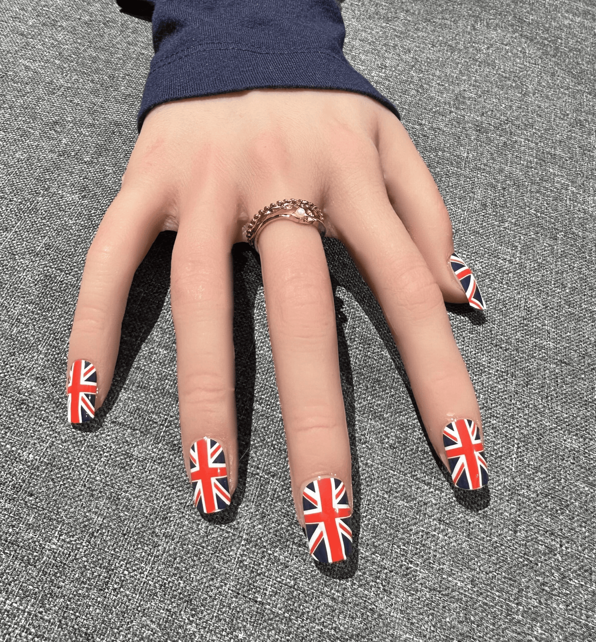 Hand wearing Union Jack nail wraps showing British flag design on fingernails