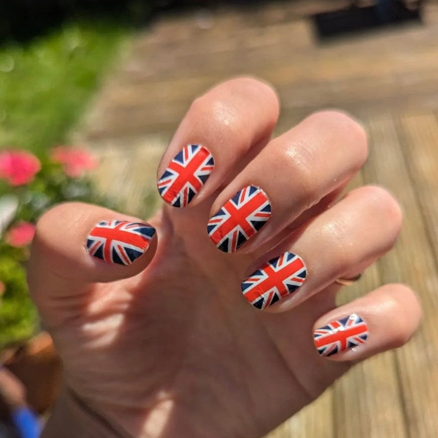 Hand wearing British Union Jack nail wraps red white blue patriotic nail design