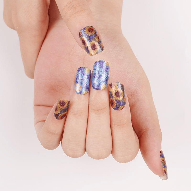 Hands displaying Van Gogh sunflower nail art wraps in blue and yellow brushstroke design
