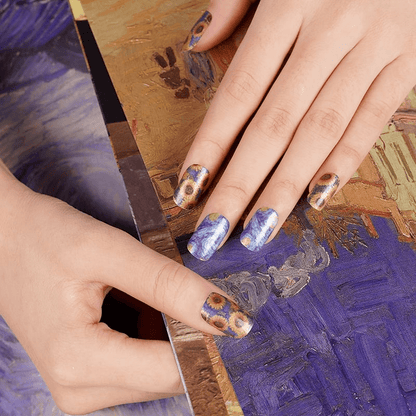Van Gogh inspired sunflower nail wraps on hands with artistic blue and yellow paint palette