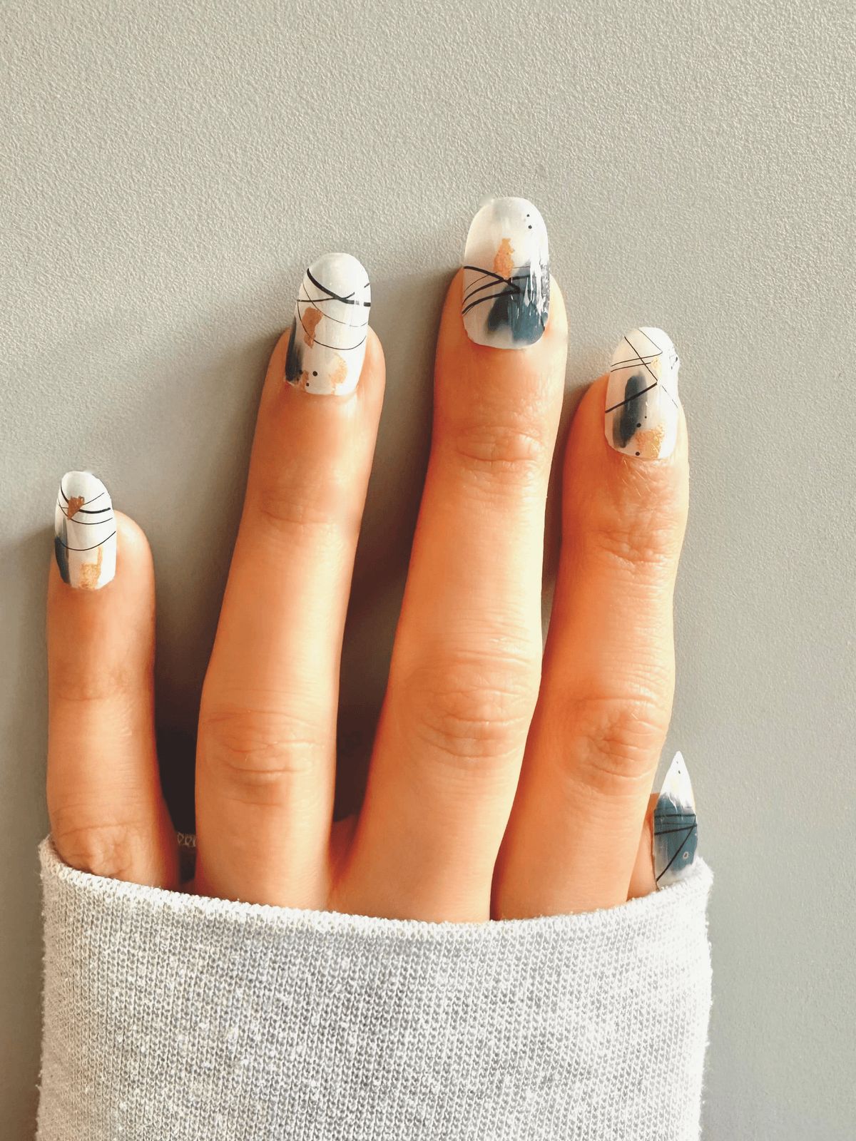 White nail wraps with abstract black line art, teal brushstrokes and gold accents