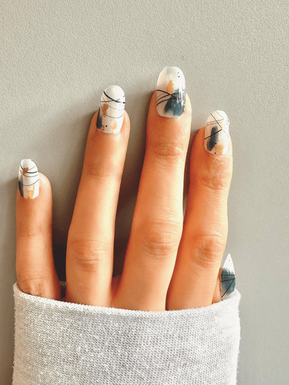 White nail wraps with abstract black line art, teal brushstrokes and gold accents