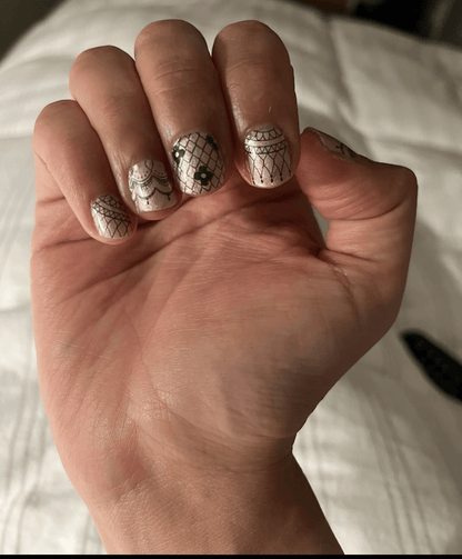 Delicate black lace nail art wraps on fingertips with vintage Victorian patterns