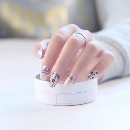 Hand wearing black lace nail wraps with Victorian pattern nail art design